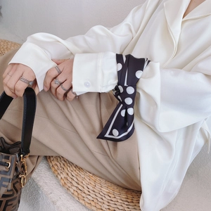 Foulard en soie à pois porté au poignet avec une chemise en satin et un pantalon kaki