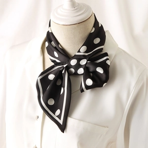 Élégante écharpe en soie noire à pois blancs nouée en nœud sur le cou d'un mannequin