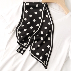 Détail d'un foulard en soie à pois noirs classiques sur un t-shirt blanc et cintre