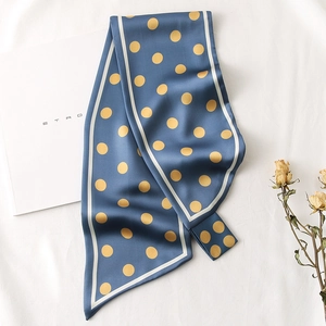 Détail d'un foulard en soie bleu marine à pois jaunes et bordure blanche sur fond blanc
