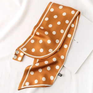 Détail d'une écharpe en soie jaune caramel à pois avec texture satinée et bordure blanche