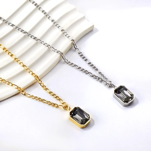 Vintage gold and silver Figaro necklaces with rectangular crystal pendants on white display