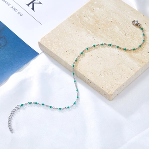 Detail view of silver stainless steel anklet with green beads and adjustable lobster clasp