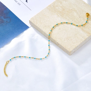 Detail of gold ankle chain with turquoise beads, lobster clasp, and extension links