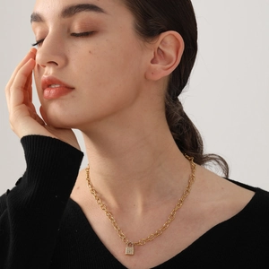 Close-up of gold chunky chain necklace with pavé crystal lock pendant on model