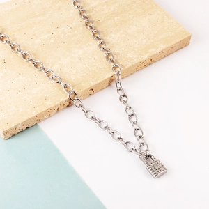 Silver link chain necklace featuring a crystal-encrusted lock pendant on a stone background