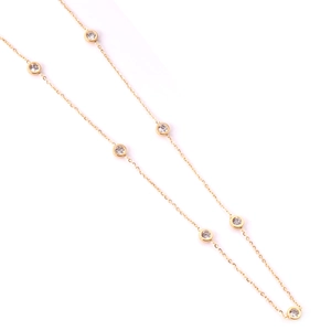 Macro detail of gold-plated necklace with white zircon bezel setting on fine metal chain