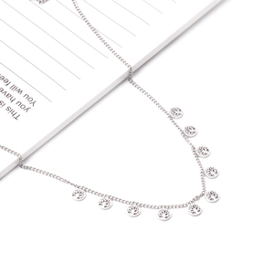 Detailed close-up of a silver Tree of Life charm necklace on a minimalist notebook background