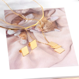Macro detail of gold geometric square necklace and stud earring set on warm background