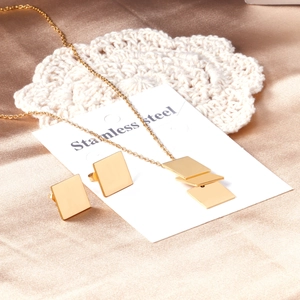 Detailed view of square gold stainless steel necklace and earrings on silk background