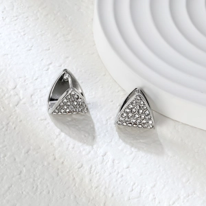 Détail de boucles d'oreilles triangulaires argentées avec pavé de cristaux blancs brillants