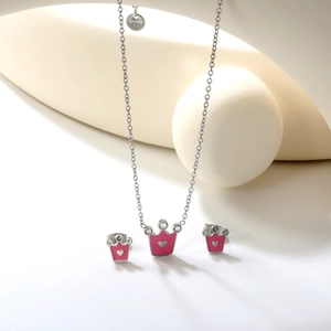 Détail d'un ensemble de bijoux en acier avec couronne, émail rose et cristaux
