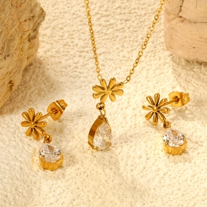 Set gioielli fiore dorato con collana e orecchini di cristallo su sfondo di pietra naturale