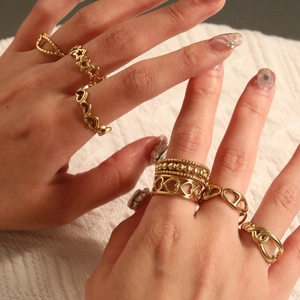 Set aus goldenen Edelstahlringen mit Herz Stern und Kettenmotiven auf weißem Textil