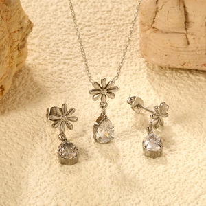 Set gioielli fiore argento con cristalli a goccia su sfondo di pietra naturale