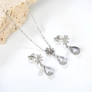 Set di gioielli in argento con ciondoli in zircone a goccia e fiori su base bianca
