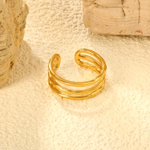 Macro detail of gold triple-layered open ring with irregular texture on stone background