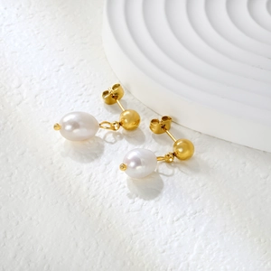 Detailed macro view of 18k gold-plated stud earrings with elegant teardrop pearl drops