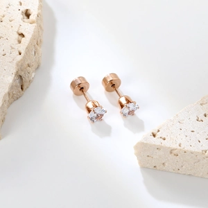 Détail de boucles d'oreilles en or rose avec cristal rond et serti à quatre griffes