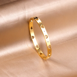 Polished gold stainless steel bangle featuring hollow heart designs and sparkling zircon accents