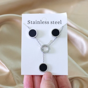 Detail of a silver stainless steel Y-necklace with black enamel round pendants