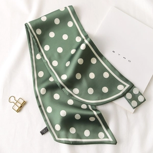 Détail d'un foulard en soie à pois vert foncé avec bordure contrastée et satin