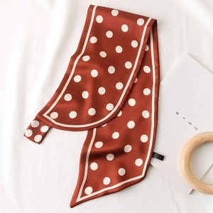 Détail d'un foulard en soie rouge brique à pois blancs avec extrémités pointues élégantes