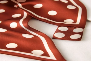 Détail de la texture d'un foulard en soie caramel à pois et son drapé fluide