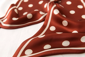 Vue macro d'un foulard à pois en soie synthétique montrant la texture lisse et le détail