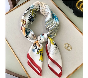 Detail view of printed silk square scarf with red borders and modern artistic illustrations