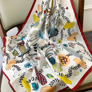 Close-up of silk scarf with red border and artistic botanical prints on leather chair