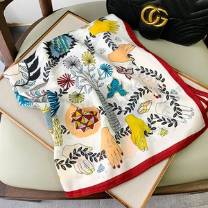 Detailed shot of an artistic print silk scarf featuring a vibrant red border on a tray