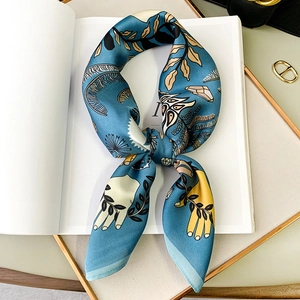 Artistic blue square silk scarf with gold leaf print placed on an open book