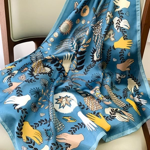 Detailed close-up of a blue silk scarf with artistic hand and star prints on a wooden chair