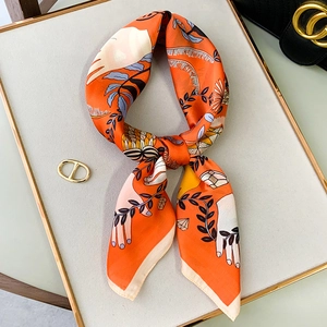 Artistic printed orange silk scarf with abstract floral patterns on elegant grey pedestal