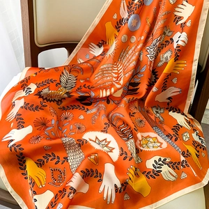 Close-up of bright orange silk scarf featuring artistic hand-painted bohemian patterns