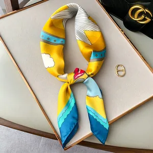 Macro detail of silky printed square scarf featuring vibrant yellow and royal blue patterns