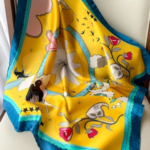 Detailed view of yellow floral silk square scarf draped on a white chair