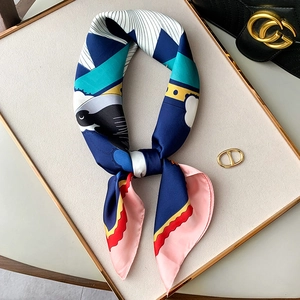 Elegant silk scarf with navy blue and pink geometric bird print on white display plate