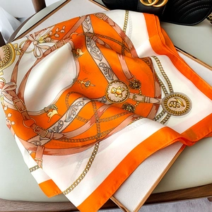 Detail of luxury square scarf featuring vintage chain patterns and orange borders on fabric