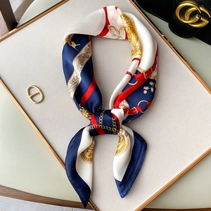 Macro view of silky twilly scarf with chain and floral print on elegant display tray