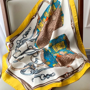 Macro detail of silk feel scarf featuring equestrian chain and handbag patterns