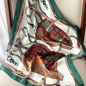 Detail of silk-like scarf featuring equestrian pattern and deep green border on leather seat