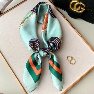 Detailed view of mint green silk scarf with golden chain print and geometric patterns