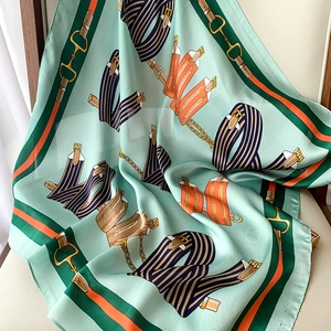 Detailed view of mint green silk scarf with luxury horse strap and chain patterns