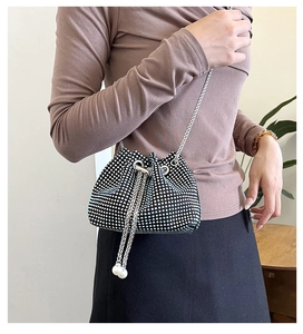 Détail d'un sac seau noir en strass avec bandoulière chaîne et perles au cordon