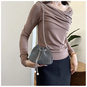 Détail d'un sac seau en strass avec bandoulière chaîne et pendentif perle cordon
