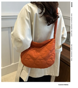 Detail of orange heart-quilted crossbody bag shown on model with wide strap and nylon finish