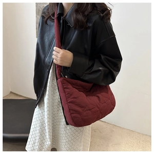 Detailed view of a dark red quilted crossbody bag featuring unique heart-shaped stitching