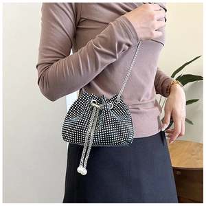 Détail d'un sac seau en strass avec cordon de perles blanches et bandoulière chaîne